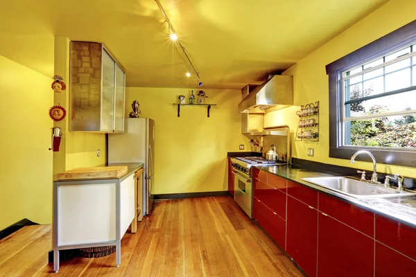 Kjøkkenroms interiør med gule vegger og røde skap . – stockfoto