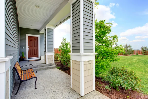 Cozy covered porch with concrete floor, columns and comfortable bench — Stock Photo, Image