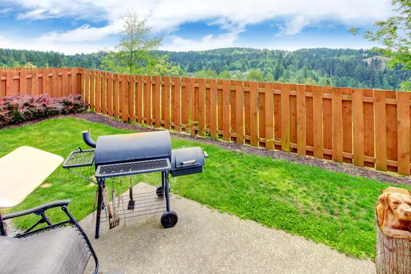 Fenced backyard with concrete patio area and barbecue. Beautiful landscape — Stock Photo, Image