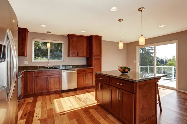 Amplia sala de cocina con barra, armarios marrones y luces colgantes . —  Fotos de Stock