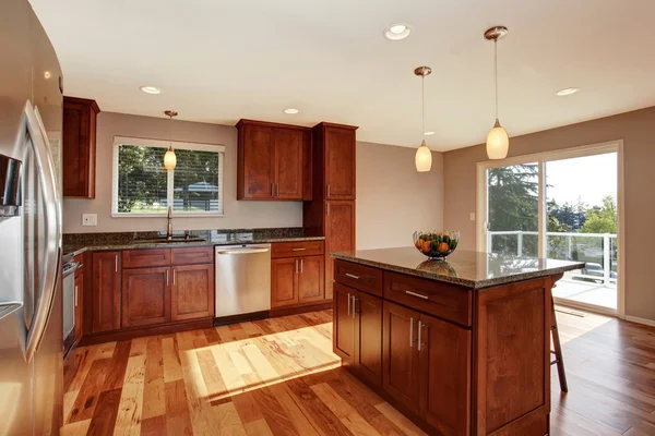 Spacious kitchen room with bar, brown cabinets and pendant lights. — Stock Photo, Image