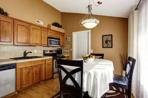 Cozinha acolhedora e sala de jantar interior com conjunto de mesa preta e armários castanhos . — Fotografia de Stock