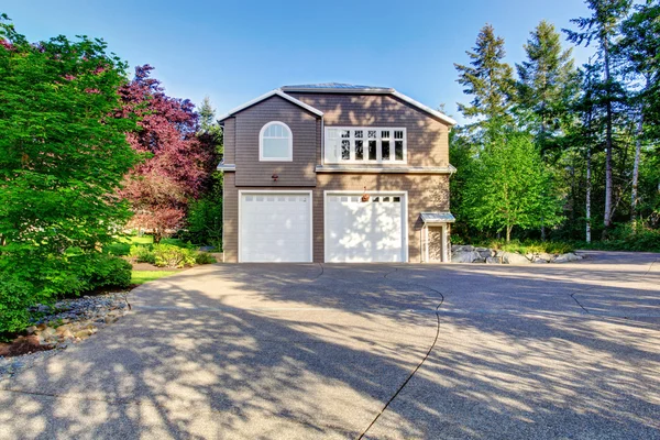 Luxury gray house with white trim and two garage spaces with concrete floor driveway. — Stock Photo, Image