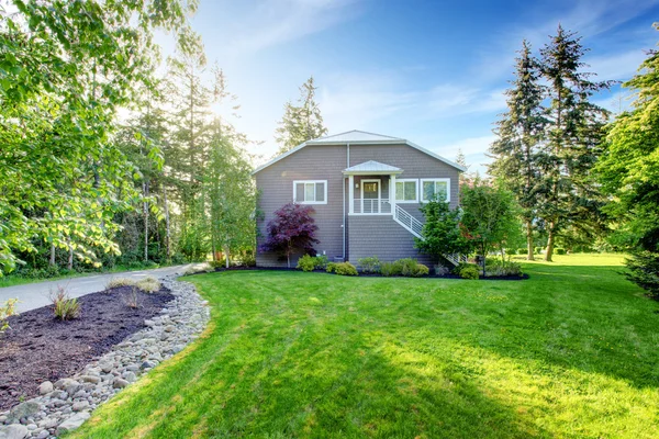 Grå stort hus exteriör med grön bakgård och uppfart. — Stockfoto