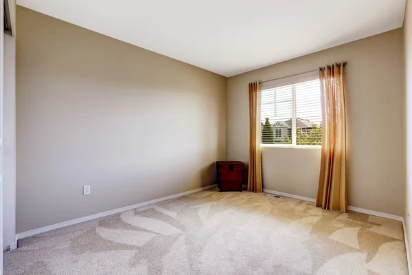 Bright empty room with one window, carpet floor and ivory walls