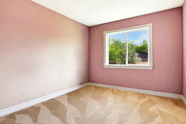 Chambre vide lumineuse avec une fenêtre, sol moquette et murs roses — Photo