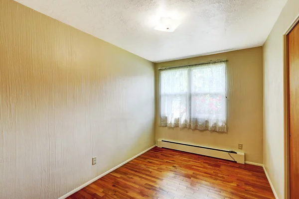 Liten tomt källarrum med lövträ golv och beige väggar — Stockfoto