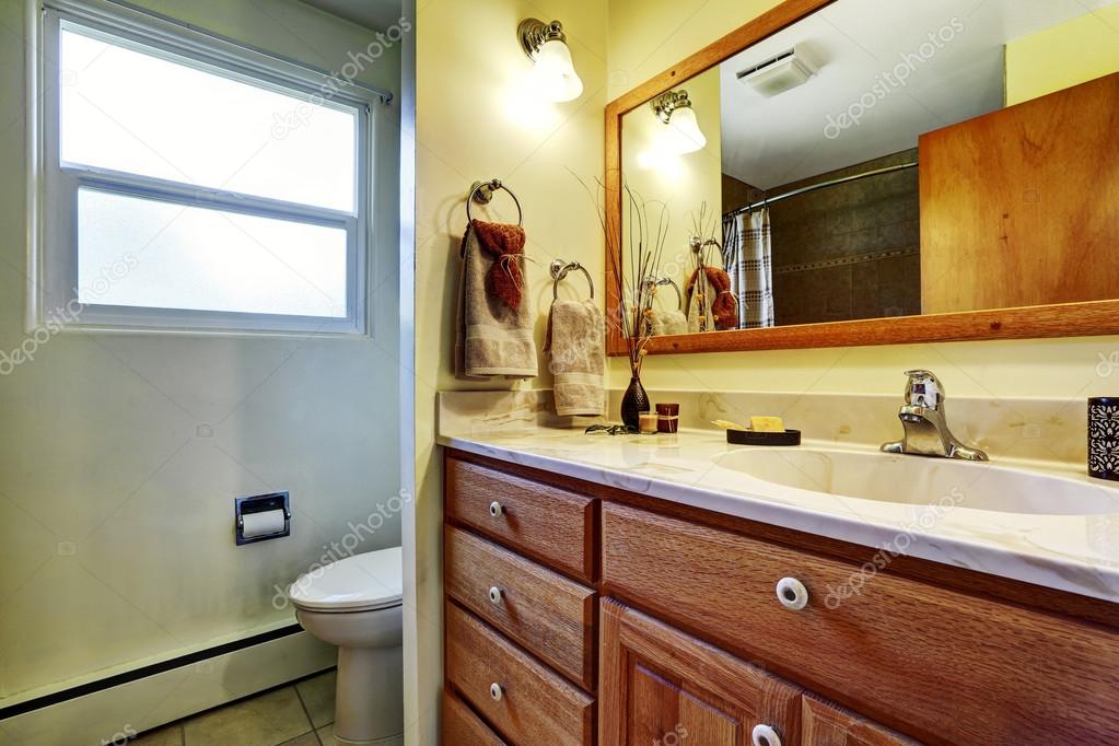 Baño sencillo con armarios marrones, aseo y una ventana . — Foto de