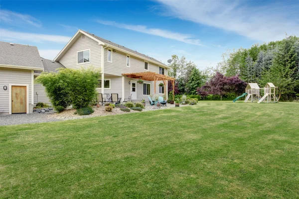 Hermosa casa patio trasero con césped bien cuidado y zona de patio — Foto de Stock