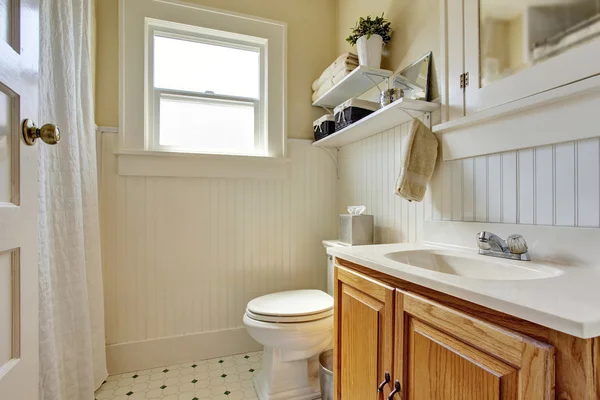 Projekt łazienki w kremowych kolorach z brązową drewnianą szafką i małym oknem. — Zdjęcie stockowe