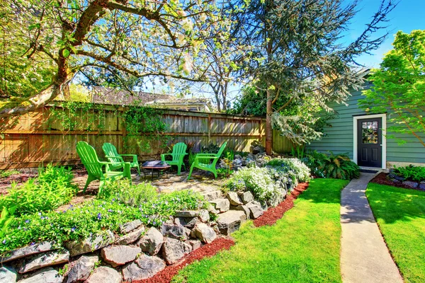 Omheinde achtertuin met groene gazon en patio gebied. Uitzicht op de blauwe schuur. — Stockfoto