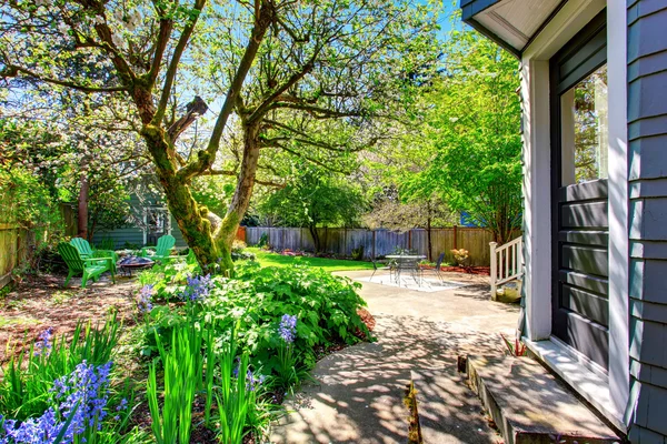 Achtertuin gebied met veel groen, bomen en terras tafel set. — Stockfoto