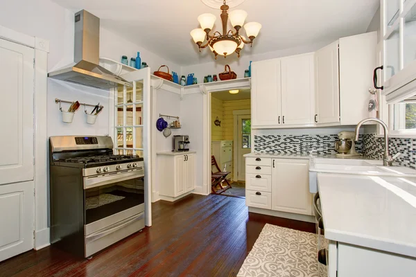 Lichte keuken kamer met witte kasten en hardhouten vloer. — Stockfoto