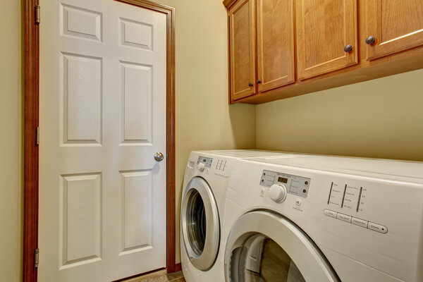 Laundry room with white appliances and light tone cabinets
