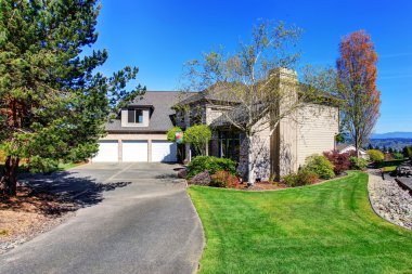 Large modern house with three garage spaces and concrete driveway.