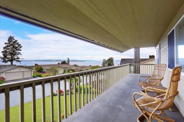 hasır sandalyeler ve ahşap korkuluklar ile rahat kaplı veranda.