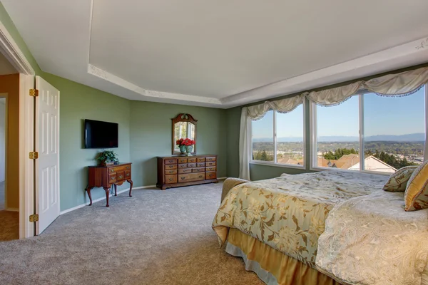 Master bedroom with green walls, vanity cabinet and floral bedding. — Stock Photo, Image