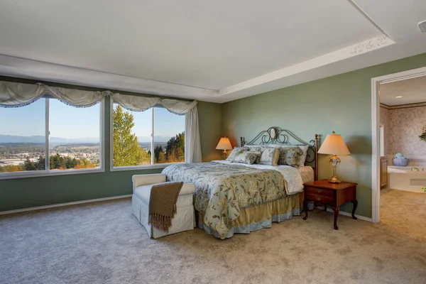 Chambre des maîtres avec murs verts, tapis beige et literie florale . — Photo