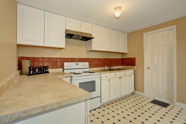 White kitchen room with tile floor and brown back splash tile.