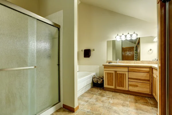 Élégante salle de bain aux tons doux avec armoires en bois franc et sol carrelé en marbre . — Photo