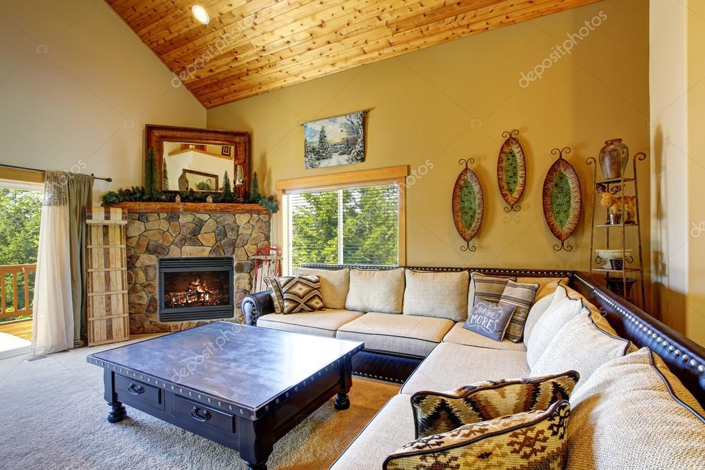 Cozy Living Room With High Wooden Ceiling And Carpet Floor Stock Cozy Living Room With High Wooden Ceiling And Carpet Floor Furnished Large Beige Sofa Black Coffee Table Drawers