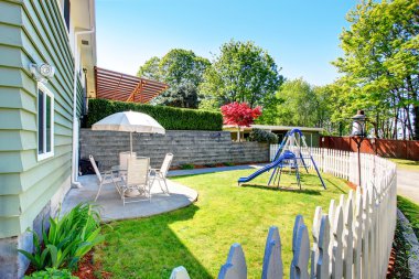 Evin dış cephesi. Veranda alanı ve çocuk oyun alanı ile çitle çevrili arka bahçesinde