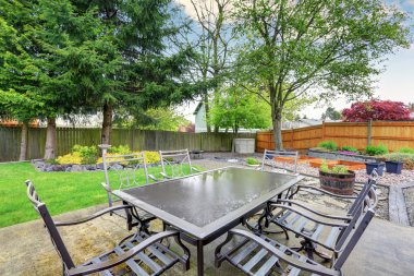 Cozy patio area with concrete floor and table set. clipart