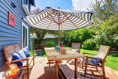 Wooden walkout deck in the backyard garden of blue siding house.