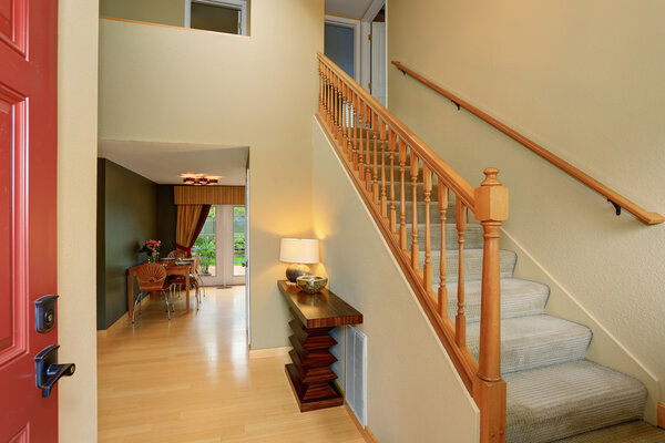 Entrance hallway in ivory tones with view of staircase and dining table set.