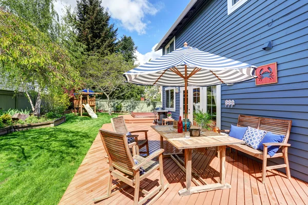 Wooden walkout deck in the backyard garden of blue siding house. — Stock Fotó