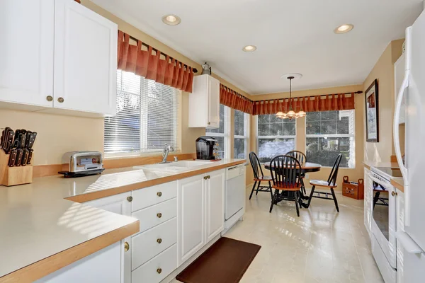 White kitchen cabinets with steel appliances and tile floor — Stock Photo, Image