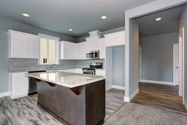 Grey and white kitchen interior with dark brown kitchen island. — Stock Photo, Image