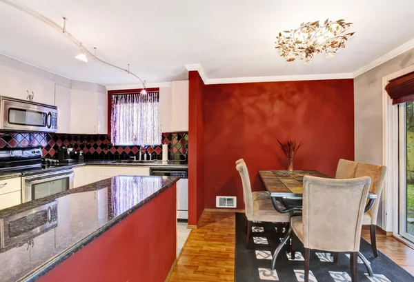 Eethoek verbonden met keuken met rode muren, vintage kroonluchter. — Stockfoto