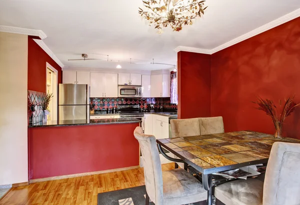 Dining area connected to kitchen with red walls, vintage chandelier. — Stock Photo, Image