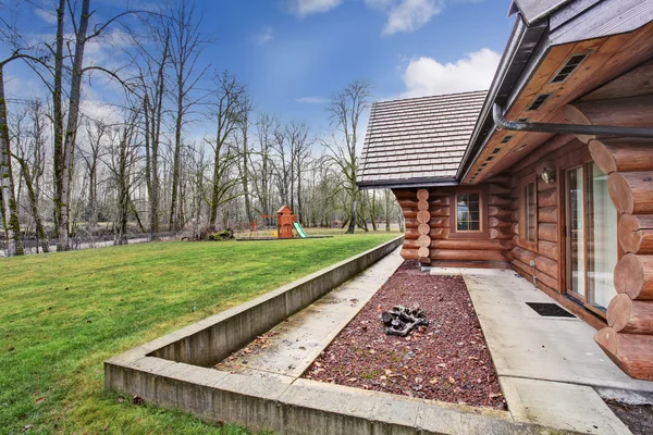Grote blokhut huis exterieur met gras gevuld achtertuin. — Stockfoto