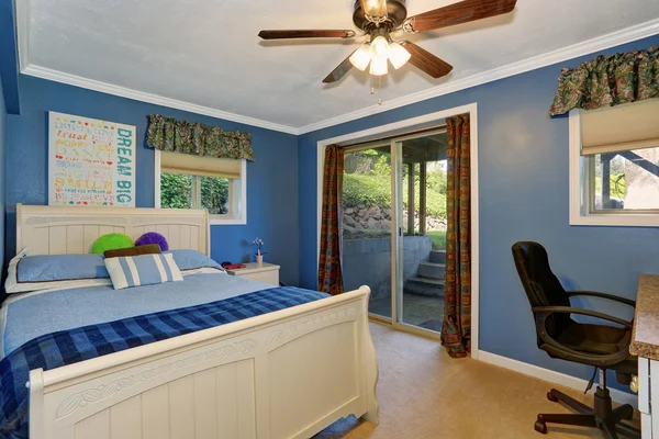 Деревянная двуспальная кровать с белой резьбой в голубой спальне — стоковое фото