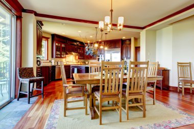 Arka planda mutfak ile bal rengi yemek masası seti görünümü.