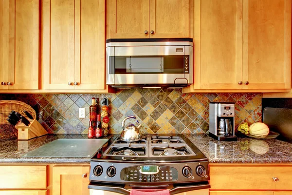 Keuken kamer met bruine kasten, roestvrijstaal, granieten aanrechtblad. — Stockfoto