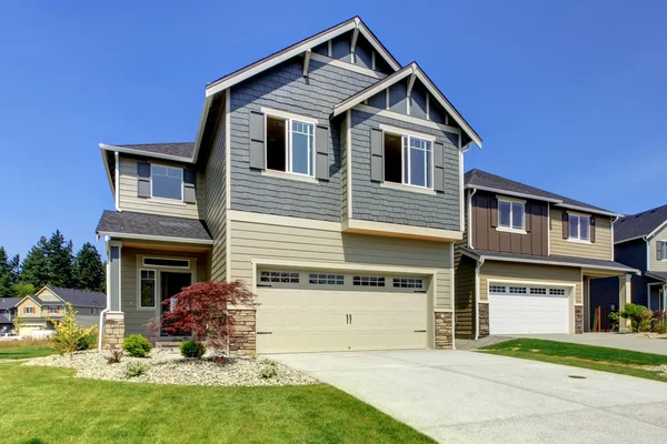 Schöne graue Hausfassade mit Stein, grünem Rasen und Einfahrt. — Stockfoto