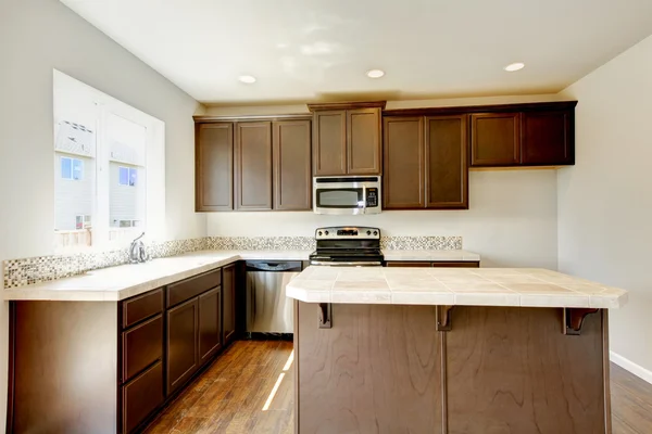 Small yet practical kitchen with brown cabinets and tile marble tops. — Stock Photo, Image