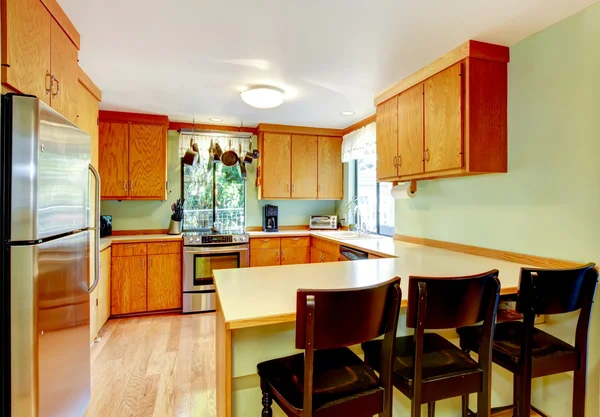 Bright kitchen with light brown cabinets and old wooden stools. — Stock Photo, Image