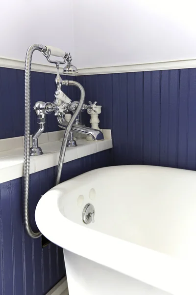 Vitt badkar med antika hårdvara, blå trä wall. — Stockfoto