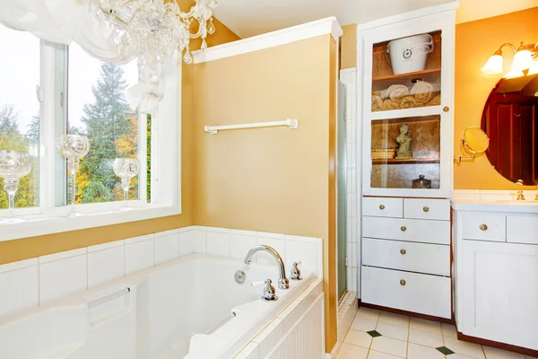 Yellow bathroom with white storage combination and elegant chandelier. — Stock Fotó