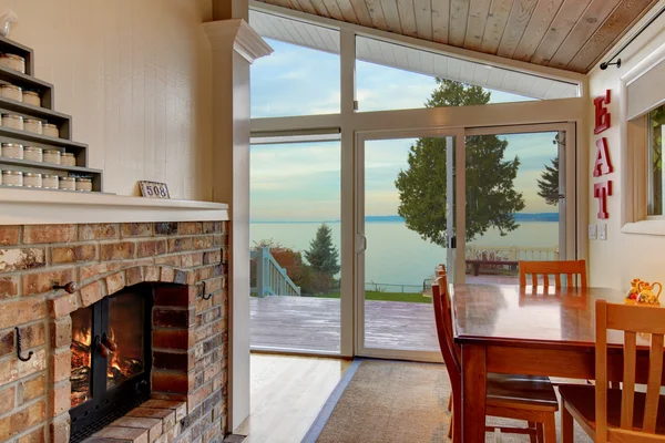 Pequeño comedor con chimenea de ladrillo y vista al agua . —  Fotos de Stock