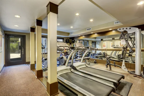 Sala de gimnasio para residentes en el edificio de apartamentos. Diferentes equipos de ejercicio y pesos — Foto de Stock