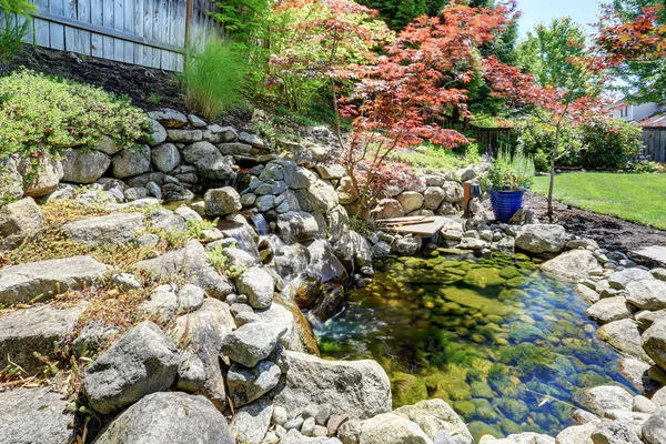 Vacker landskapsdesign på bakgård. Utsikt över en liten damm med klippor. — Stockfoto