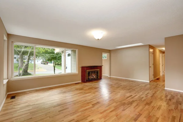 Prázdný interiér obývacího pokoje s cihlovým krbem a podlahou tvrdého dřeva. — Stock fotografie