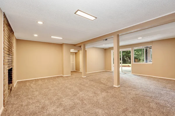 Quarto espaçoso vazio com lareira de tijolo e piso de carpete — Fotografia de Stock