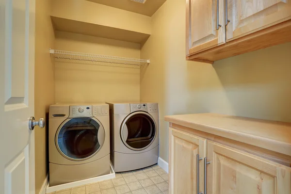 Béžová prádelna s moderními přístroji a dlaždicemi na podlaze. — Stock fotografie