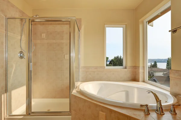 Spacious creamy bathroom with corner bathtub. — Stock Photo, Image